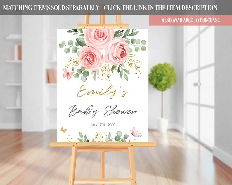 May include: A white sign with a floral design in shades of pink and green. The text "Emily's Baby Shower" is written in gold script with the date "JULY 17TH-2020" below it.
