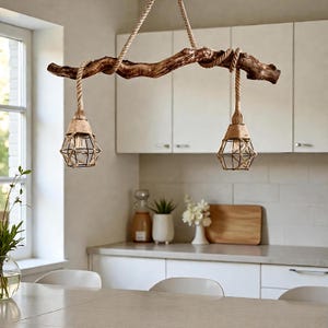 Puede incluir: Lámpara de araña rústica de rama de madera con dos luces colgantes. Cada luz tiene una pantalla de jaula de metal envuelta en cuerda, suspendida por una cuerda gruesa. La lámpara cuelga en una cocina, agregando una estética natural y rústica.