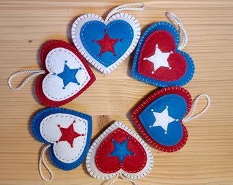 May include: Six felt heart ornaments in red, white, and blue with a white star in the center of each heart. The hearts are sewn together to form a circle.
