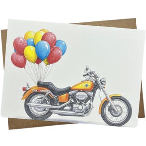 May include: Greeting card featuring an orange motorcycle with a black seat and chrome accents. A cluster of colorful balloons in red, yellow, and blue floats above the motorcycle, suggesting a celebration or special occasion.