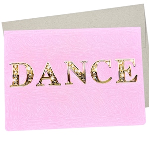 May include: A pink card with the word "DANCE" in gold letters with rhinestones. The letters are in a bold, serif font.
