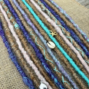 May include: A set of synthetic dreadlocks in brown, blue, pink, and turquoise colors. The dreadlocks are decorated with small seashell and starfish charms.