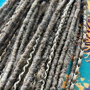 May include: A bundle of brown and white synthetic dreadlocks with white braided accents.