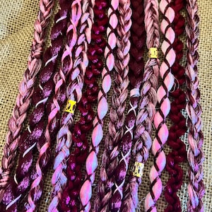May include: A collection of burgundy and pink braided hair extensions with gold beads. The braids are made of synthetic hair and are ready to be added to your hair.