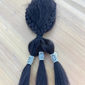 May include: Three black braids with silver metal beads. Each bead has a different design.