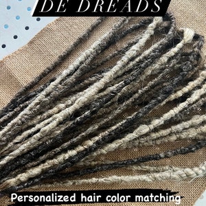 May include: A collection of double-ended dreadlocks in shades of black, grey, and white. The text DE DREADS appears at the top, with Personalized hair color matching and Custom requests printed at the bottom of the image display.