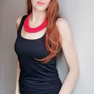 Puede incluir: Una mujer con un top negro de tirantes y un collar de crochet rojo brillante.