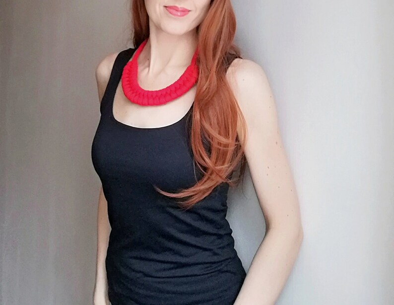Puede incluir: Una mujer con un top negro de tirantes y un collar de crochet rojo brillante.