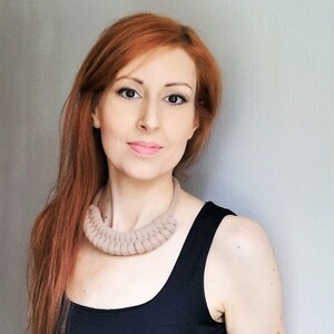 Puede incluir: Una mujer con el pelo largo y rojo que lleva un top negro de tirantes y un collar de ganchillo beige.