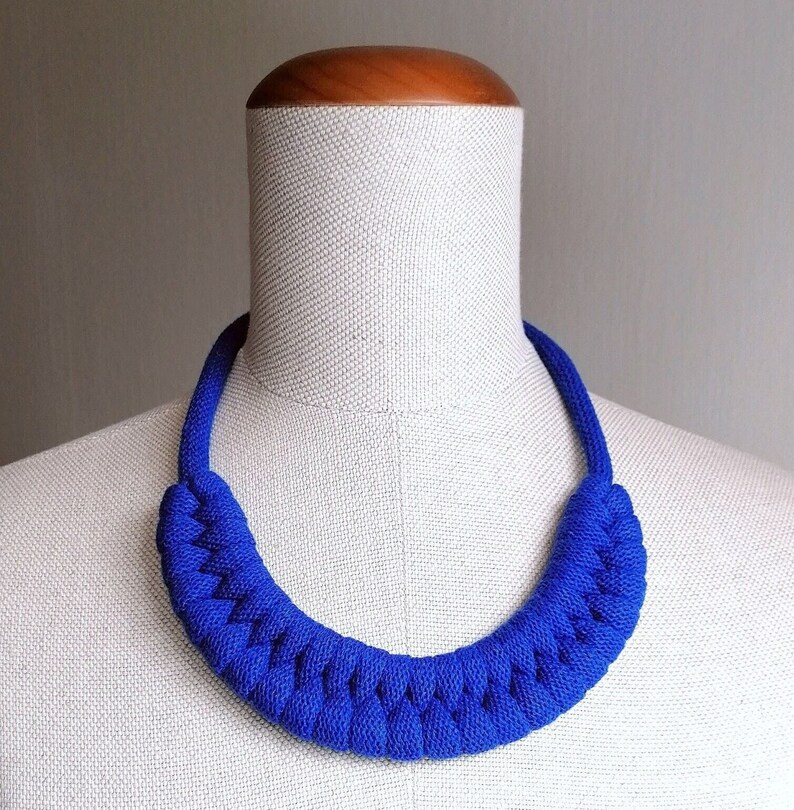Puede incluir: Un collar azul brillante anudado hecho de tela. El collar se muestra en un maniqu&iacute; blanco.