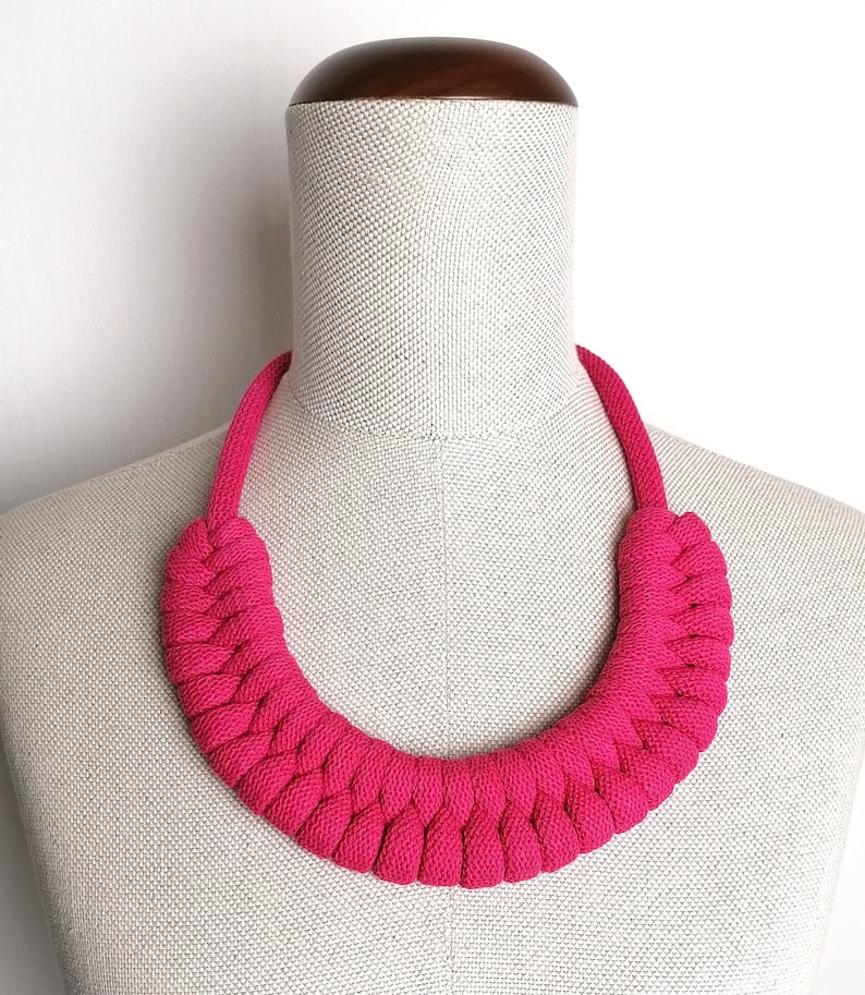 Puede incluir: Un collar de cuerda trenzada de color rosa brillante. El collar est&aacute; hecho de una cuerda gruesa y suave y est&aacute; dise&ntilde;ado para sentarse alto en el cuello.