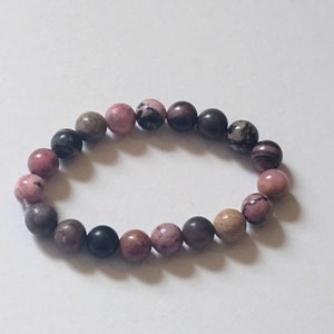 May include: A pink, brown, and black beaded bracelet with round beads.