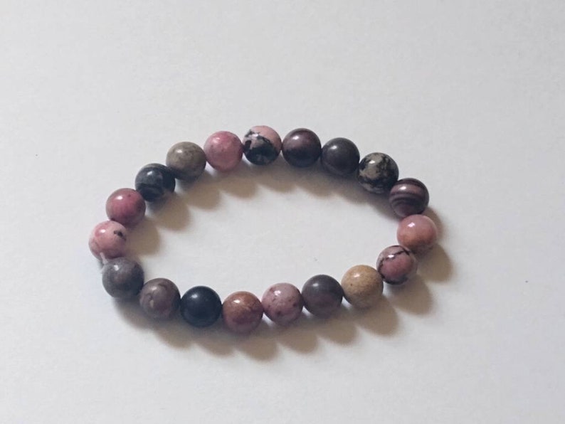 May include: A pink, brown, and black beaded bracelet with round beads.
