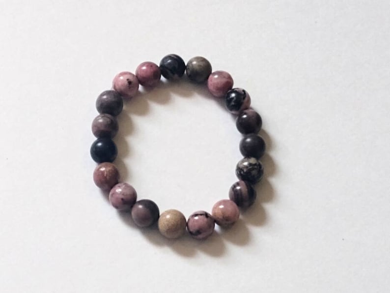 May include: A pink, black, and brown beaded bracelet. The beads are round and have a natural, polished look.