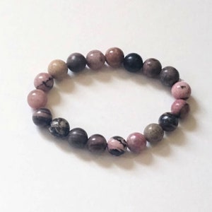 May include: A pink, brown, and black beaded bracelet with round beads.