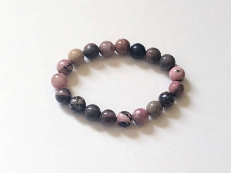 May include: A pink, brown, and black beaded bracelet with round beads.