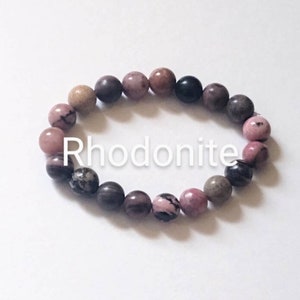 May include: A pink, brown, and black rhodonite gemstone bracelet. The bracelet is made of round beads and is strung on elastic.