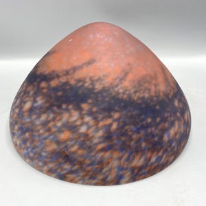 May include: A dome-shaped glass lamp shade featuring a mottled, frosted finish with blended hues of deep blue, soft orange, and white. The surface displays a textured, speckled pattern throughout, creating a diffused appearance across the curved form.