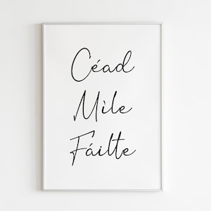 Può includere: Una stampa incorniciata bianca con la frase irlandese "Cead Mile Failte" scritta in corsivo nero.