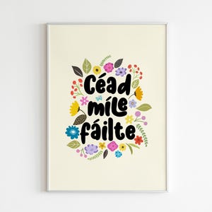 May include: A white poster with a floral wreath design featuring colorful flowers and leaves. The text "Cead mile failte" is written in black lettering inside the wreath.