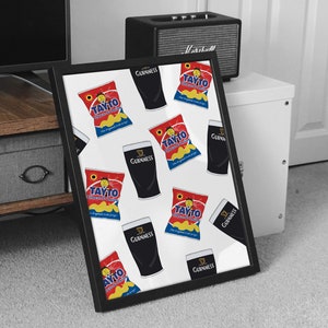 May include: A framed print with a white background and a repeating pattern of black Guinness pint glasses and red and yellow Tayto Cheese & Onion crisps bags. The text "Tayto Cheese & Onion" and "Guinness" is visible on the bags and glasses.