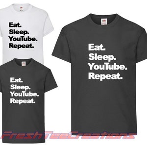 May include: Three t-shirts with the text "Eat. Sleep. YouTube. Repeat." printed on them. The shirts are in different sizes and colours, with one white, one dark grey, and one light grey.