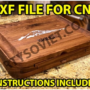 Pode incluir: Uma tábua de cortar de madeira com um design de montanha e o texto "BRIDGES" gravado nela. A tábua é feita de madeira escura e tem um acabamento natural. A tábua é projetada para ser usada para cortar e servir alimentos. O texto "DXF FILE FOR CNC" e "INSTRUCTIONS INCLUDED" também é visível na imagem.