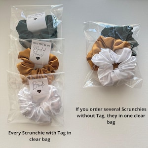 May include: Several scrunchies in clear plastic bags. One bag contains a dark green scrunchie, a gold scrunchie, and a white scrunchie. The other bags contain individual scrunchies with tags that say "Will you be my Maid of Honor?" and "Bride".