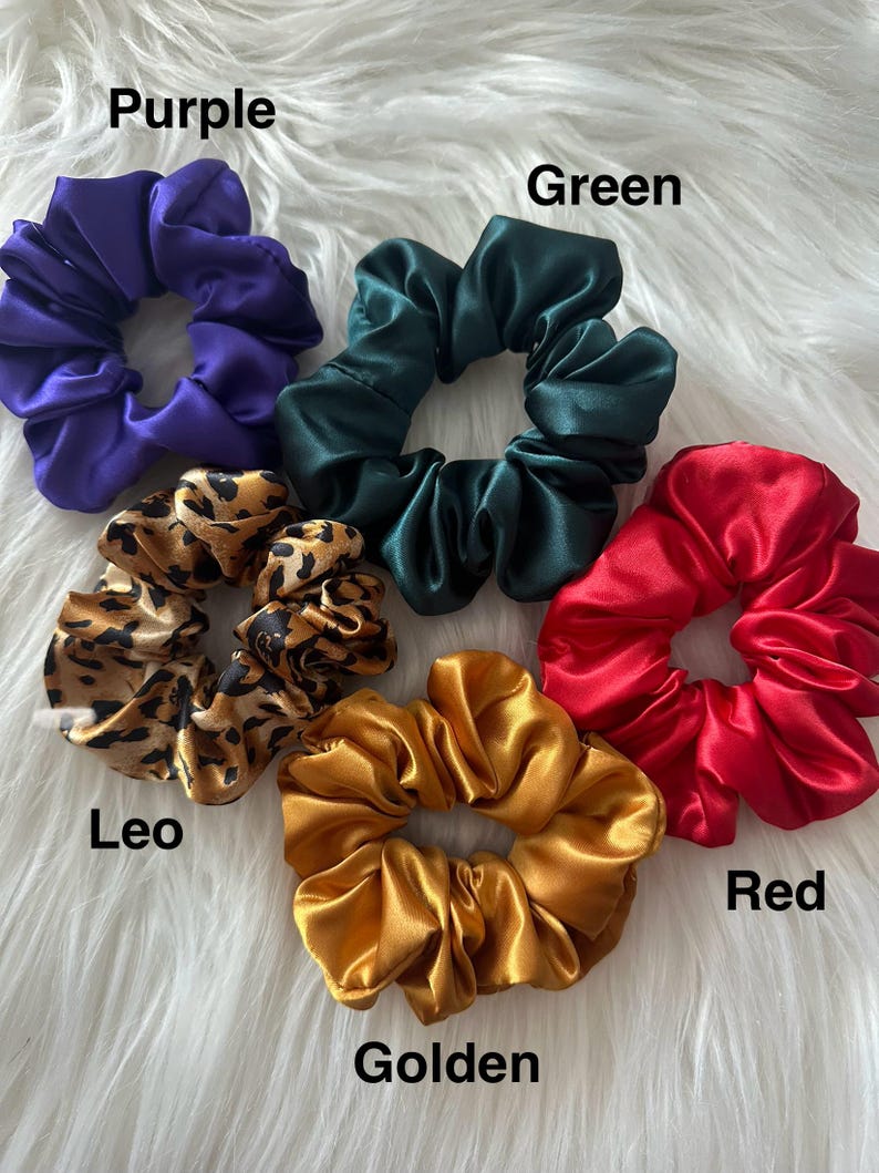 May include: A collection of satin scrunchies in various colors, including purple, green, red, and golden. One scrunchie features a leopard print. The names of the colors are written on the image.