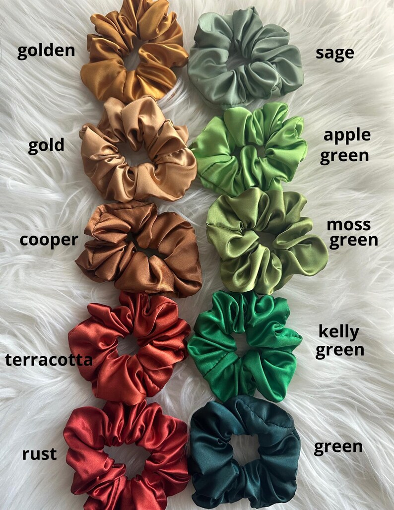 May include: A collection of satin scrunchies in various colors, including golden, gold, copper, terracotta, rust, sage, apple green, moss green, kelly green, and green. Each scrunchie is labeled with its corresponding color name.