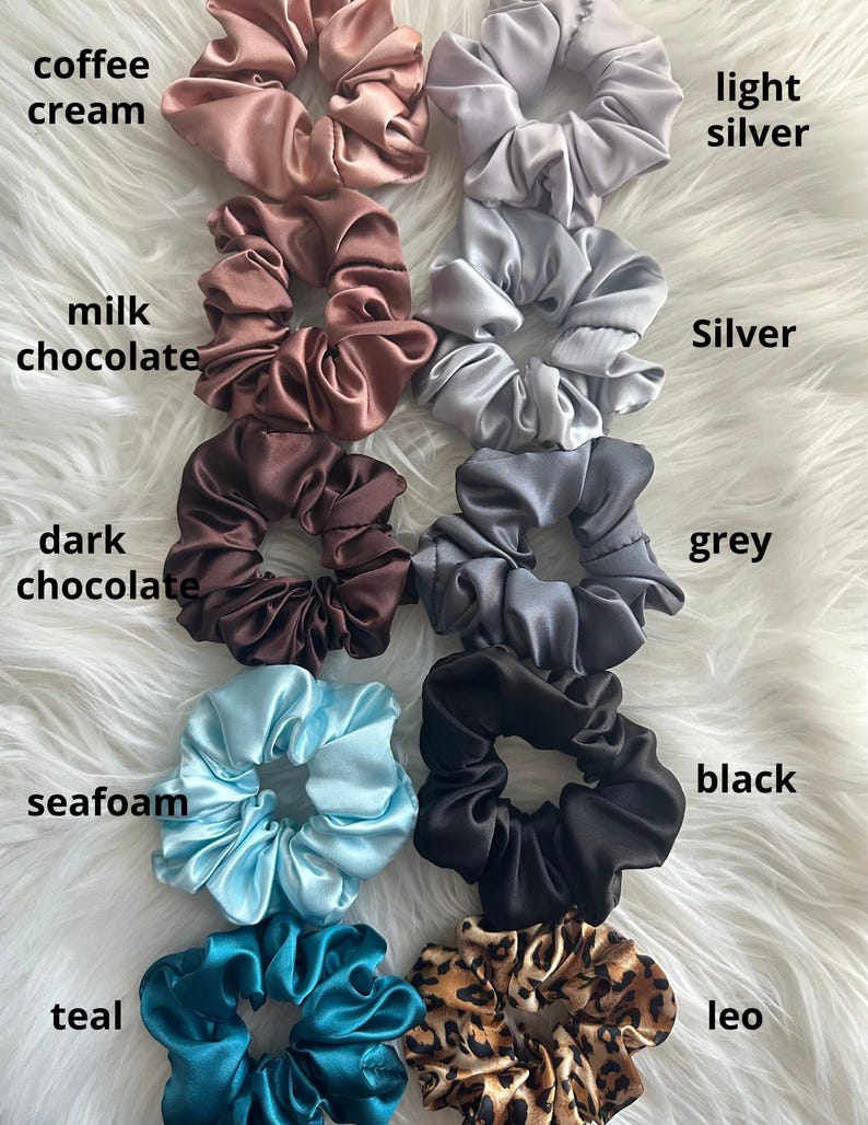 May include: A collection of satin scrunchies in various colors, including coffee cream, milk chocolate, dark chocolate, seafoam, teal, light silver, silver, grey, black, and leo. Each scrunchie is labeled with its color name.