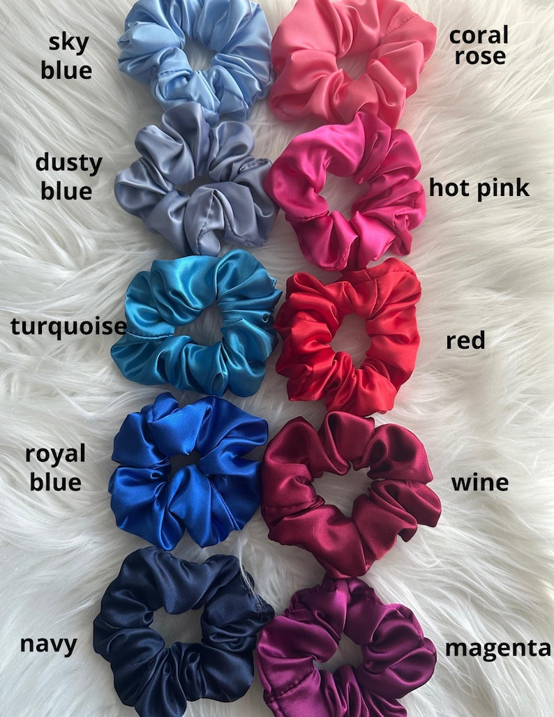 May include: A collection of satin scrunchies in various colors, including sky blue, dusty blue, turquoise, royal blue, navy, coral rose, hot pink, red, wine, and magenta. Each scrunchie is labeled with its corresponding color name.