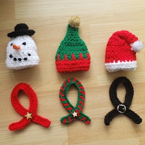May include: Six crocheted hats in various colors and styles, including a snowman, elf, Santa, and two scarves.