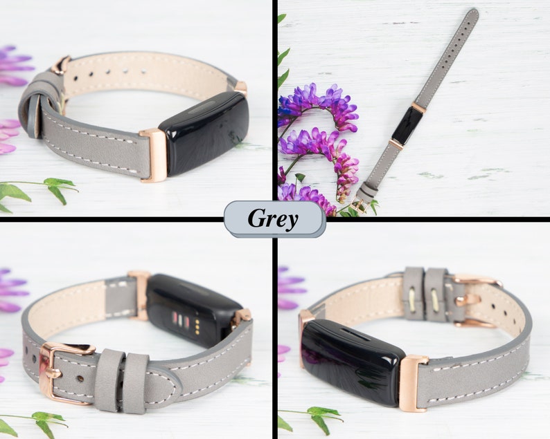 May include: A grey leather watch strap with rose gold hardware. The strap is shown on a white wooden surface with purple flowers.