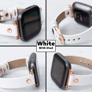 May include: White leather watch band with rose gold accents and studs. The band is compatible with a square-shaped smartwatch.