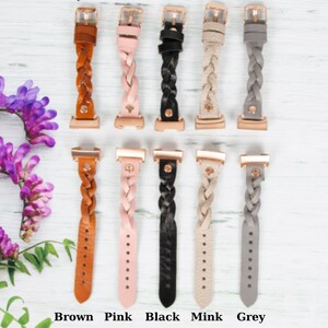 May include: Five braided leather watch bands in different colors: brown, pink, black, mink, and gray. Each band has a rose gold buckle.