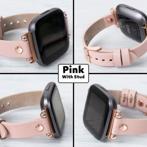 May include: Pink leather watch band with rose gold accents and studs. The band is compatible with Fitbit Versa smartwatches.