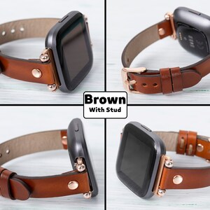 May include: Brown leather watch band with rose gold studs and buckle. The band is compatible with Fitbit Versa smartwatches.