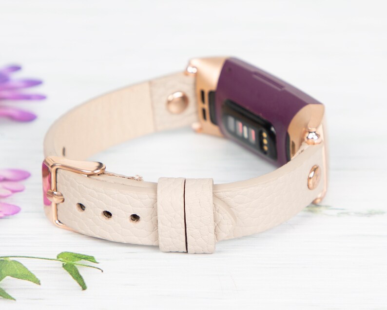 Puede incluir: Una banda de cuero beige con una hebilla de oro rosa y un rastreador de fitness morado. La banda est&aacute; dise&ntilde;ada para un reloj inteligente.