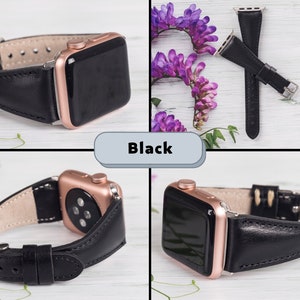 Puede incluir: Banda de reloj Apple de cuero negro con una esfera de color oro rosa. La banda se muestra sobre una superficie blanca con flores moradas.