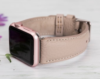 May include: A rose gold Apple Watch with a beige leather band. The band has a stitched edge and a buckle closure.