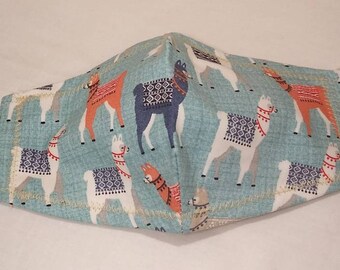 May include: A blue fabric face mask with a pattern of colorful llamas. The mask has white elastic straps with blue toggle closures.