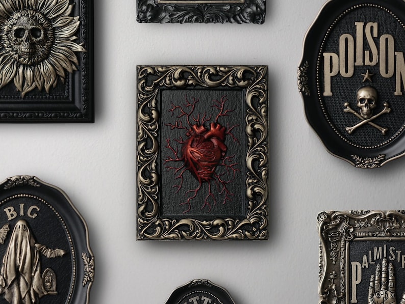 Peut inclure: Une collection d'&oelig;uvres d'art murales encadr&eacute;es sur le th&egrave;me gothique et macabre. Les cadres sont noirs et dor&eacute;s avec des d&eacute;tails orn&eacute;s. Les &oelig;uvres d'art comprennent un cr&acirc;ne avec un tournesol, un c&oelig;ur avec des veines, un cr&acirc;ne avec des os crois&eacute;s et le mot "Poison", et un fant&ocirc;me avec le mot "Big".