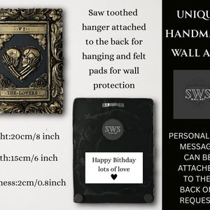 Pu&ograve; includere: Un'opera d'arte da parete rettangolare con cornice dorata e un rilievo di due teschi a forma di cuore, etichettata VI e THE LOVERS. Il retro include un gancio a dente di sega, feltrini e un'etichetta con Happy Bithday lots of love.