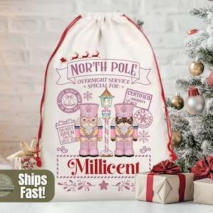 May include: A white Christmas gift bag with a red drawstring and trim. The bag is decorated with a festive design including the words "North Pole Overnight Service" and two nutcracker figures. The name "Millicent" is printed below.