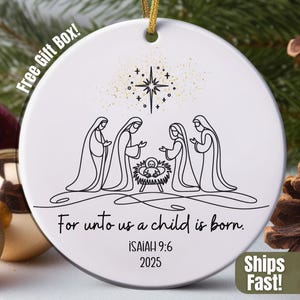 May include: White ceramic Christmas ornament with a gold string. The ornament features a black line drawing of the Nativity scene, a star, and the text "For unto us a child is born." The text "ISAIAH 9:6 2025" is also included.