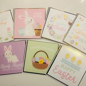 May include: A collection of square Easter greeting cards with gold borders. Designs include bunnies, chicks, Easter eggs, and floral elements. Text includes "Easter Party," "Happy Easter," and "Easter Egg Hunt."