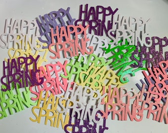 May include: A pile of colorful paper cutouts that say "Happy Spring" in various colors, including purple, pink, green, yellow, and white. The cutouts are decorated with glitter.