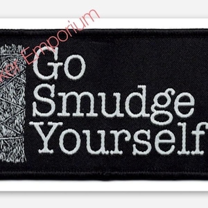 May include: Black rectangular patch with white embroidered text that reads "Go Smudge Yourself" next to an illustration of a sage bundle. The patch has a white border.