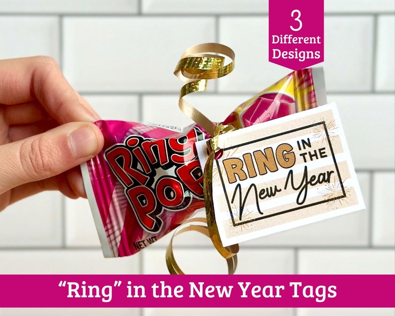 May include: A printable New Year's Eve gift tag with the text "Ring in the New Year" in gold lettering on a striped background. The tag is tied to a pink and white Ring Pop candy with gold ribbon.
